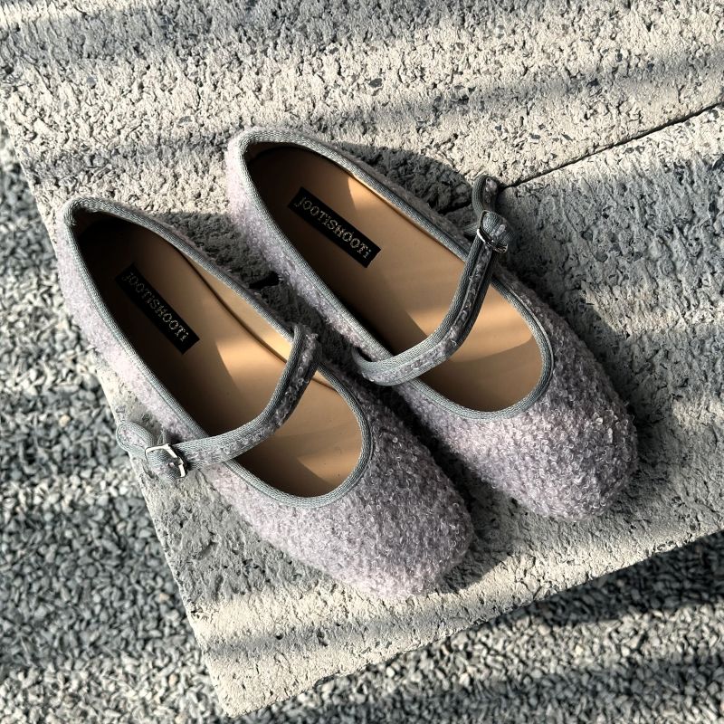 Pair of gray mary janes shoes with a strap on a textured surface