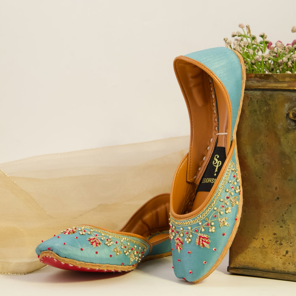 Pair of turquoise embroidered khussas with a decorative box on a light background