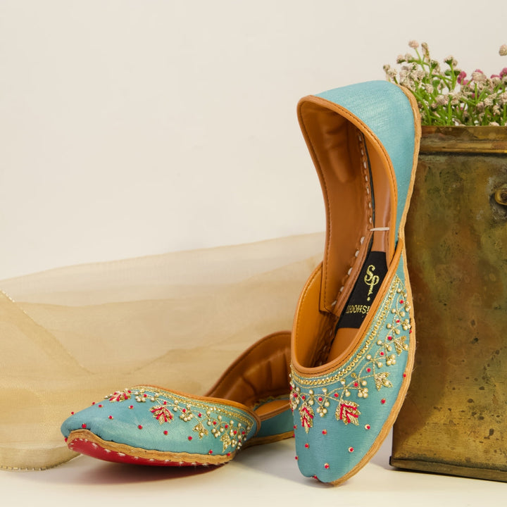 Pair of turquoise embroidered khussas with a decorative box on a light background