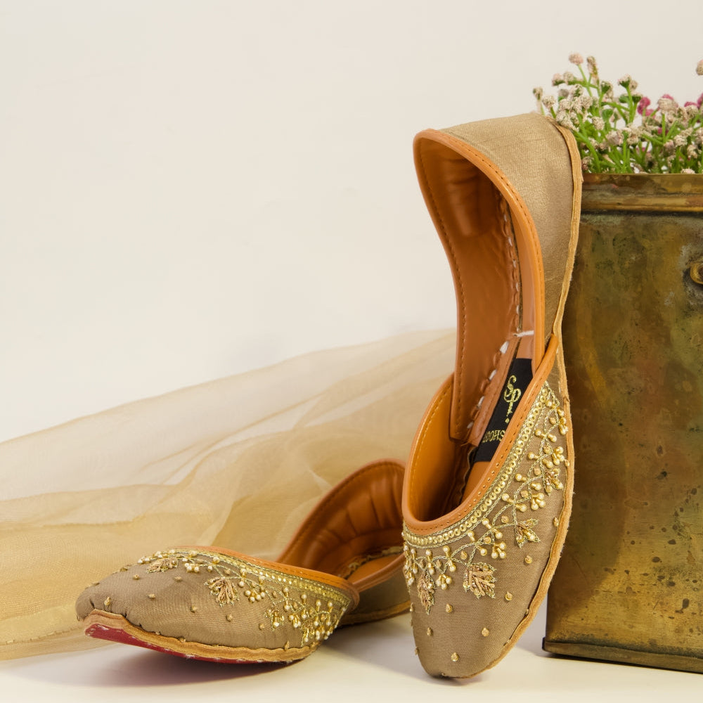 Pair of embroidered khussas with gold detailing on a light background